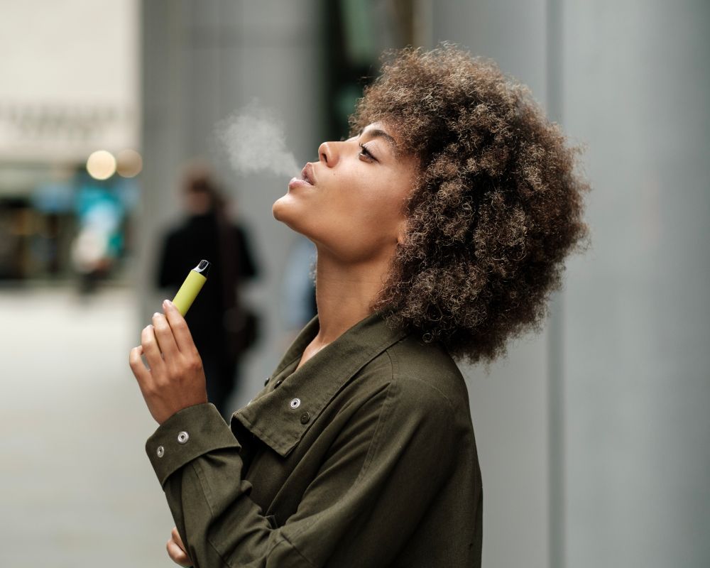 Chica fumando un cigarrillo electrónico.